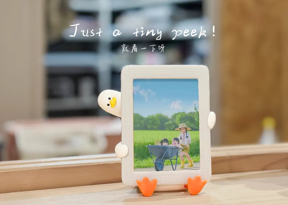 مینی فیگور اردک خسته مدل "فقط یه نگاهِ ریز…" (قاب عکس و هولدر گوشی) 🦆🖼️📱✨